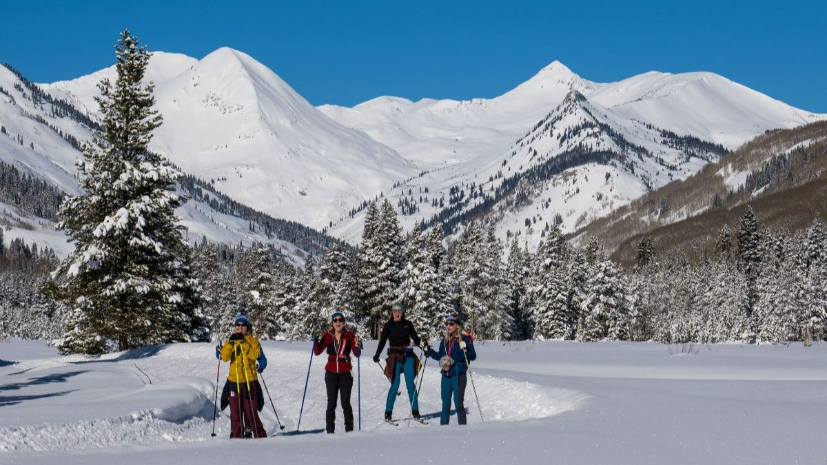 Skiers on groomed trails with Paradise Divide backdrop near Crested Butte